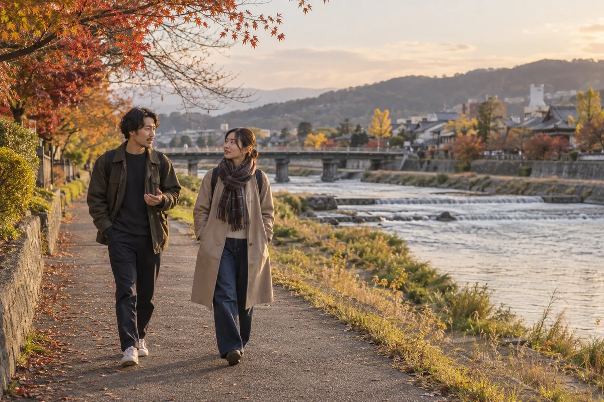 夕方の川沿いの道を、話しながら並んで歩く二人の友人